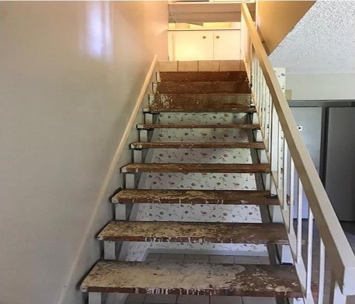Stairway that is stripped of the brown and dirty carpet. Wood stairway. 