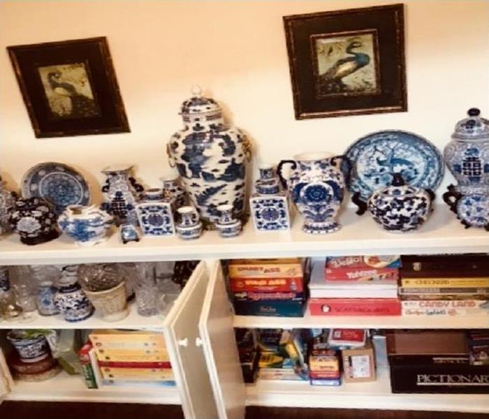 Lower cabinet filled with items that are antique or vintage with vases and plates displayed above that are fragile. 