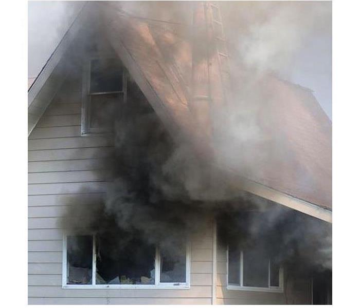 A Home with black smoke coming out of broken shattered windows