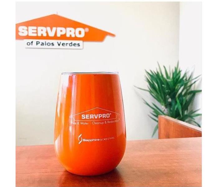 Small orange drinking tumbler with the background of the orange SERVPRO of Palos Verdes logo. 