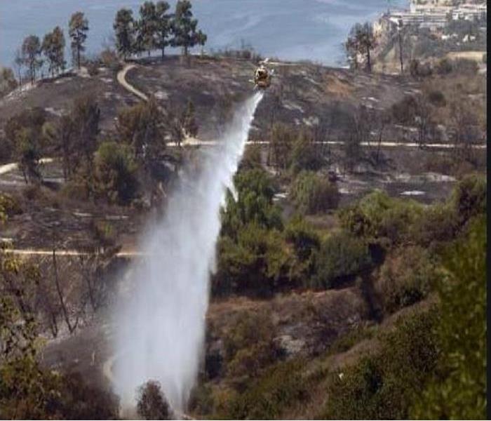 Helicopter pouring water over the hillside of Palos Verdes Estates dousing a brush fire. 