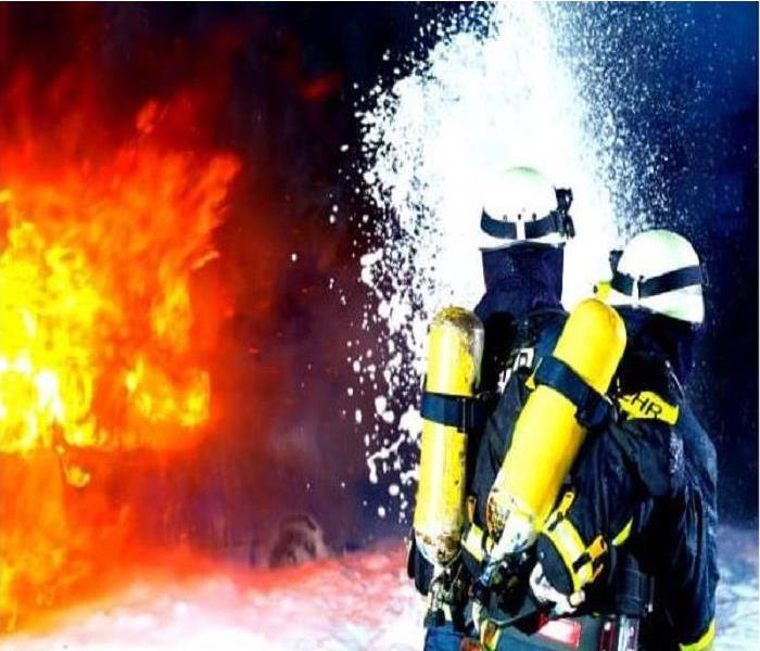 2 firefighter spraying down a very large fire with foam.