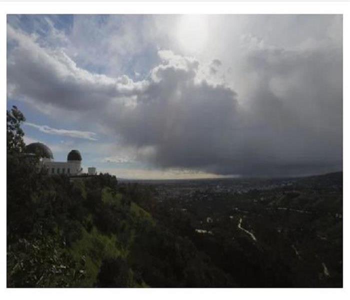 Mountainside of Griffith Park Observatory under dark clouds.
